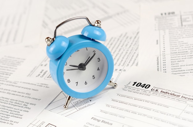 1040 Individual income tax return form and blue alarm clock