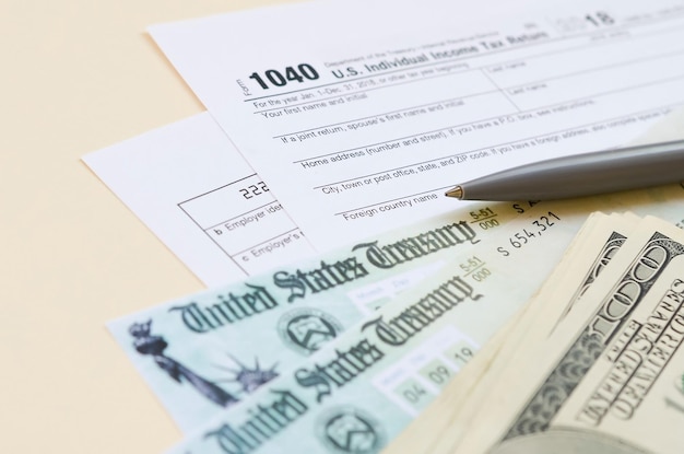 1040 Individual Income tax return form with Refund Check and hundred dollar bills on beige background