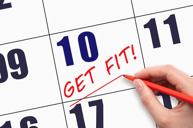 10th day of the month Hand writing text GET FIT and drawing a line on calendar date Save the date