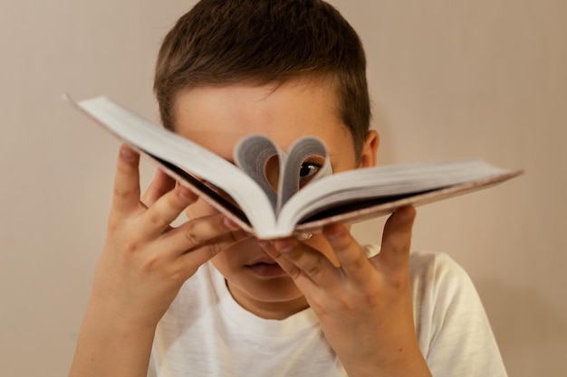 A 10yearold boy has turned the pages of a book and looks through them as if through binoculars