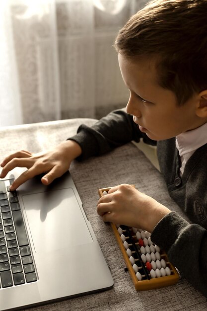 A 10yearold boy learns mental math with a laptop and abacus