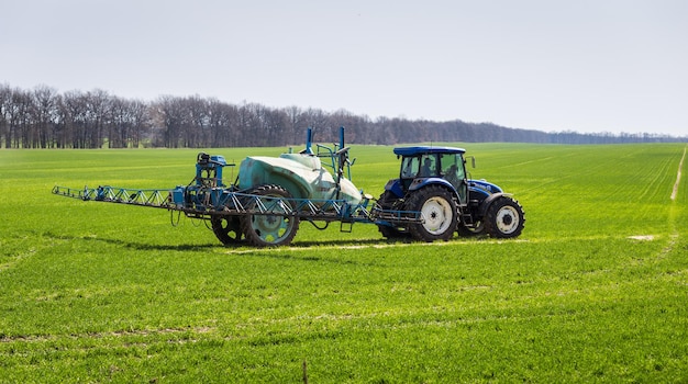 11 of April2018 Vinnitsa Ukraine Tractor spraying insecticide to the green field agricultural natural seasonal spring background