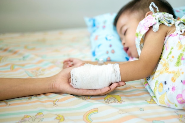 A 15yearold Asian boy is sick and is being treated at the hospital A mother's hand is holding her wrapped son's hand