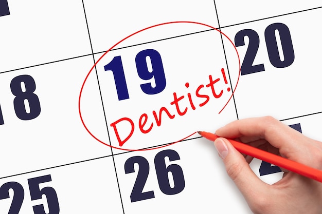 19th day of the month Hand writing text DENTIST and circling the calendar date