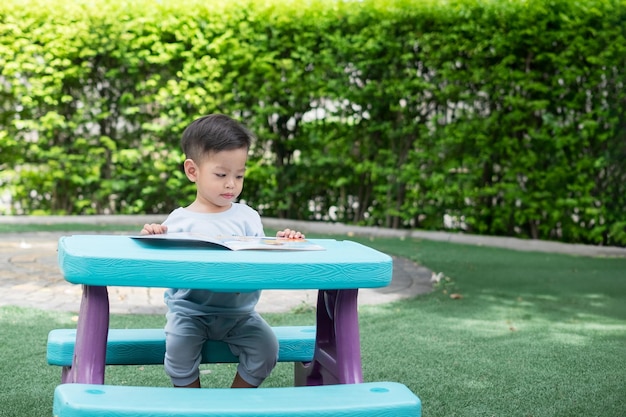 1yearold Asian boy sitting in his house reading a book