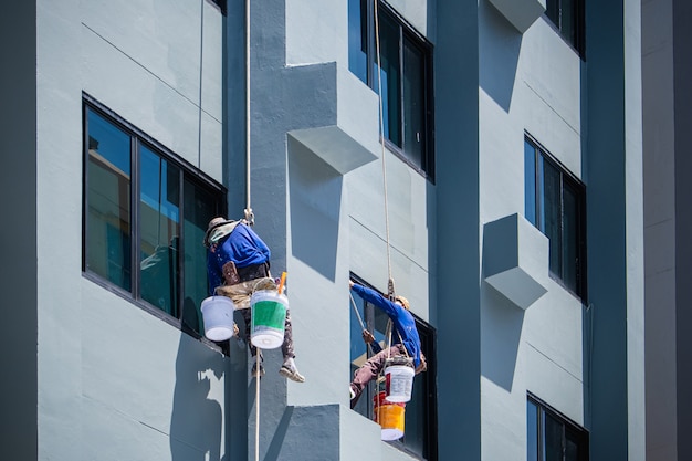 2 painters are hanging on ropes.