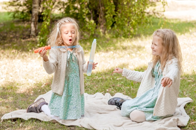 2 sisters at a picnic playing with soap bubbles Summer holidays 3 blonde girls