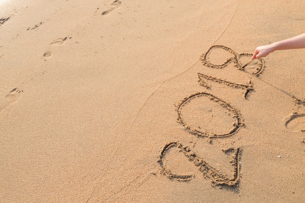 2018 message written in the sand at the beach background