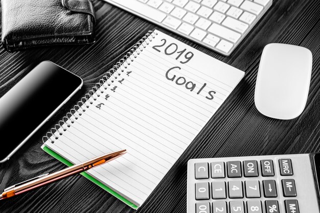 2019 GOALS on his notebook. New year resolutions concept. Top view.