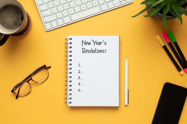 2020 new year notebook with list of resolutions and objects on yellow background