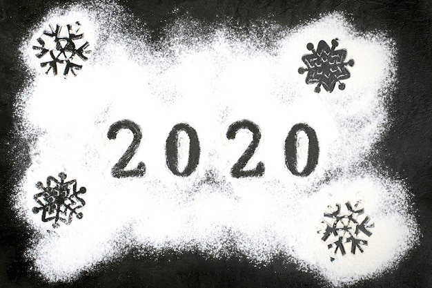 2020 text made with flour with decorations on a black background.  