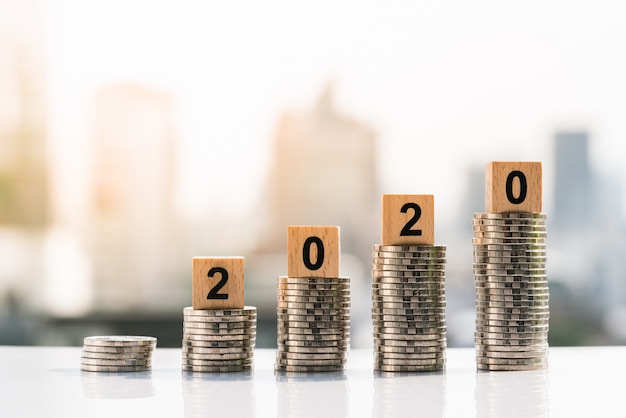 2020 wooden blocks on top of coin stack on city backgrounds.