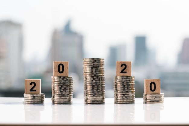 2020 wooden blocks on top of coin stack on city backgrounds.