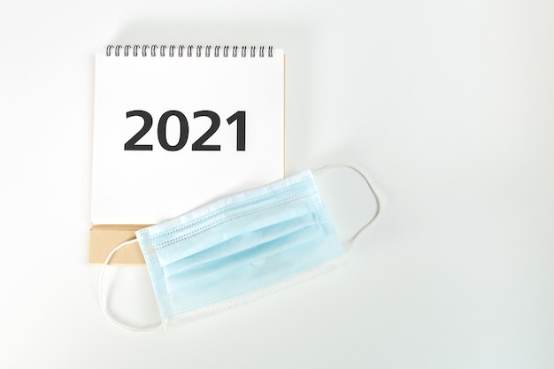 2021 calendar aside next to surgical mask on white background