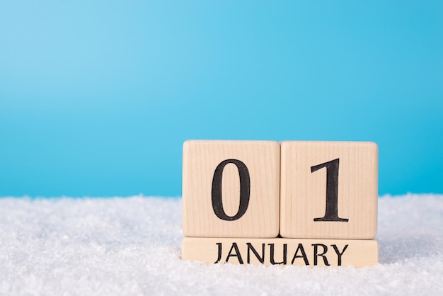 2021 coming soon concept. Close up photo of wooden cube calendar showing date of a new year isolated on blue background with snow