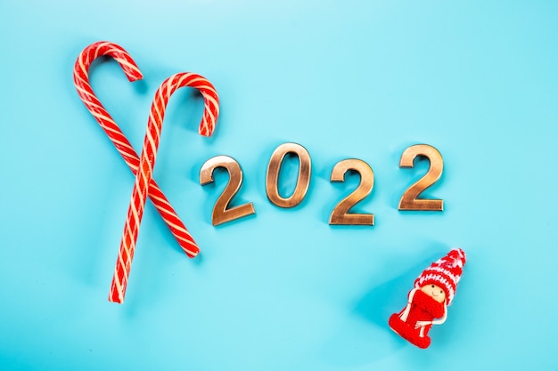 2022 golden figures,numbers, candy cane and gnome or swedish tomte, on a blue background.Happy New Year celebration. Gold numbers , holiday background, postcard,party.Shiny numbers,copy space