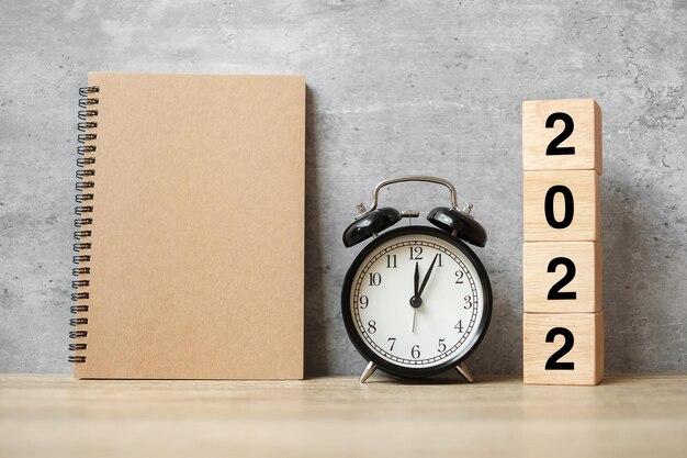 2022 Happy New Year with blank notebook, black retro alarm clock and wooden number. countdown, Resolution, Goals, Plan, Action and Mission Concept