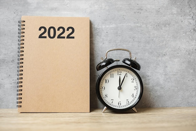 2022 Happy New Year with blank notebook, black retro alarm clock and wooden number. countdown, Resolution, Goals, Plan, Action and Mission Concept