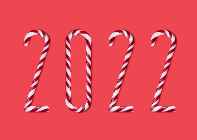 2022 made from sweet caramel canes, candies on red background