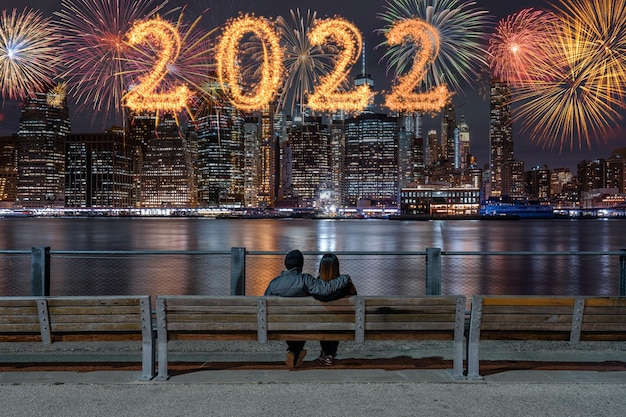 2022 written with Sparkle firework with multicolor of fireworks on back side couple sitting