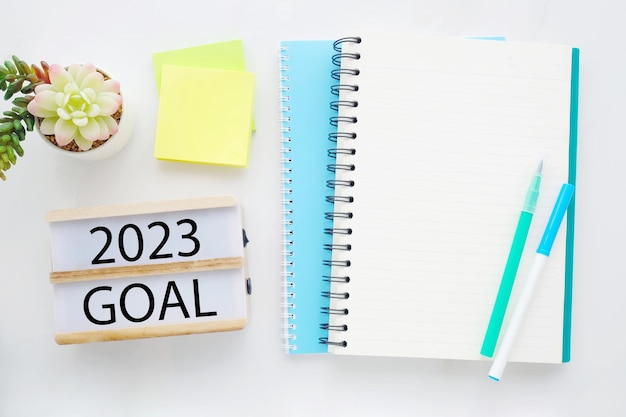 2023 goal on wood box blank notebook paper on white marble table background