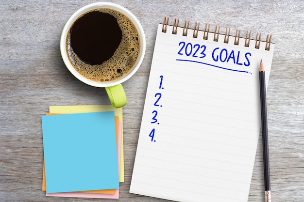 2023 goals list in a notebook with pen and coffee on table in office workplace