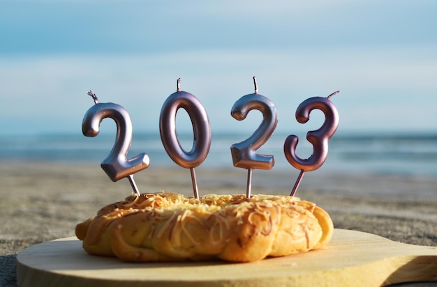 2023 Happy New Year with bread and candles on the beach