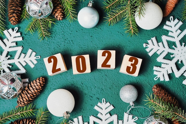 2023 new year composition branch pine tree cones snowflakes and balls on green background