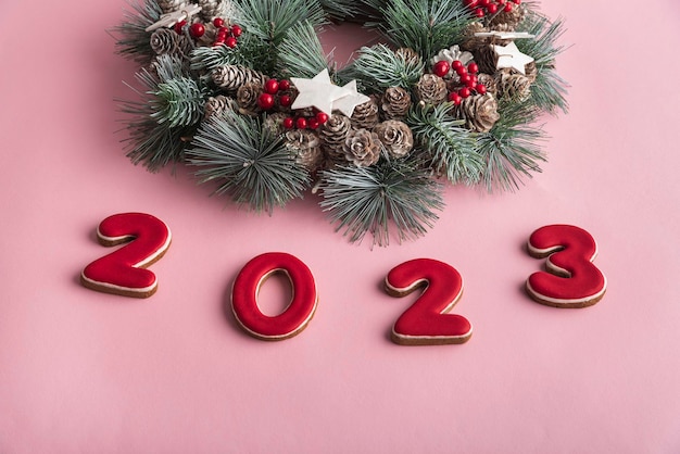 2023 new year from gingerbread and Christmas wreath on pink background Happy New Year 2023