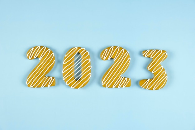 2023 number made of gingerbread cookie with white icing on blue background Merry Christmas and Happy New Year