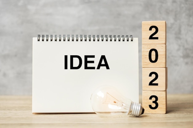 2023 text wood cube blocks and IDEAS word with lightbulb on table New Year New Ideas Creative Innovation Imagination inspiration Resolution Strategy and goal concept