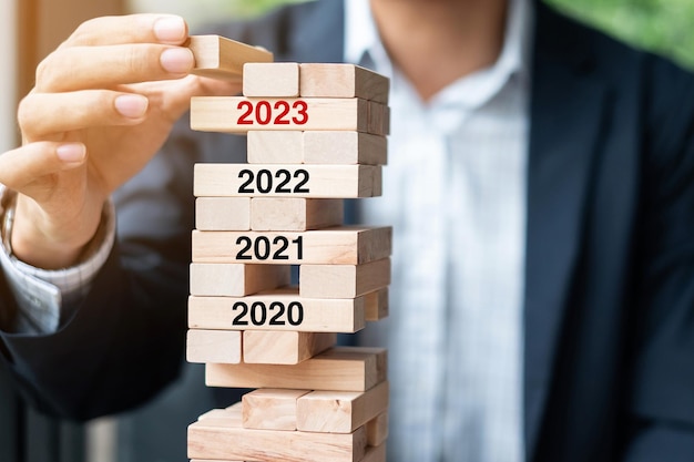 2023 year Goals Business planning Risk Management Solution and strategy Concepts Businessman hand placing or pulling wooden block on the tower