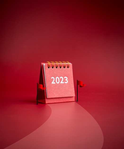 2023 year small red desk calendar standing between finish flags on road to success on red background minimalist vertical style Challenge winning motivation goals and leadership concept