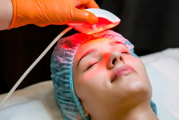 2025 years old woman receiving a nonsurgical rejuvenation procedure RF face lifting with the use of electric device equipment hardware facial massage