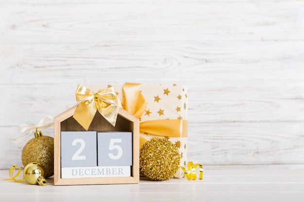 25 december Christmas composition on colored background with a wooden calendar with a gift box toys bauble copy space