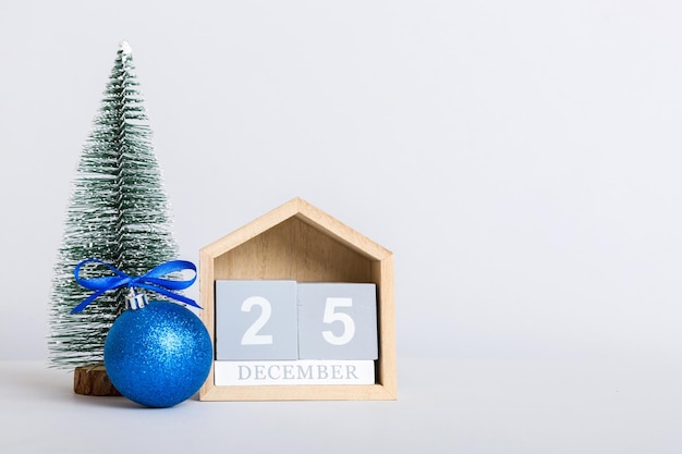 25 december Christmas composition on colored background with a wooden calendar with a gift box toys bauble copy space