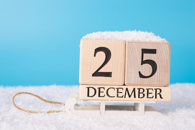 Photo the 25th of december concept its christmas day. close up photo of calendar showing date of christmas on wooden white sledges and blue sky