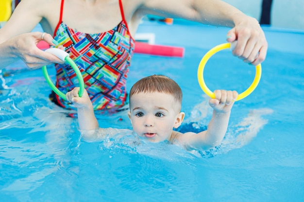 A 2yearold boy learns to swim in a pool with a coach Swimming lessons for children Swimming school for children Educational swimming courses for children