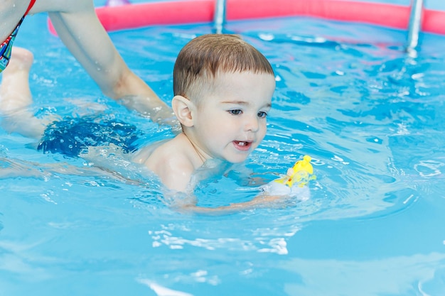 A 2yearold little boy is learning to swim in the pool Swimming lessons for young children Swimming school for children