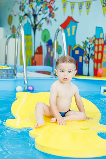 A 2yearold little boy is learning to swim in the pool Swimming lessons for young children Swimming school for children