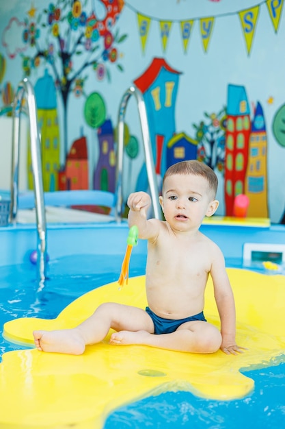 A 2yearold little boy is learning to swim in the pool Swimming lessons for young children Swimming school for children