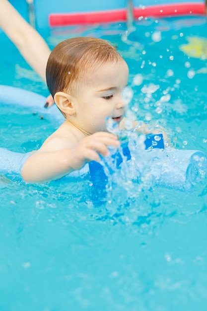 A 2yearold little boy learns to swim in a pool with a coach Swimming lessons for children