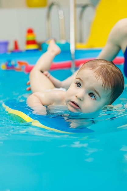 A 2yearold little boy learns to swim in a pool with a coach Swimming lessons for children