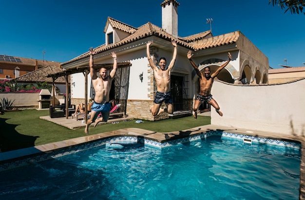 3 friends jumping into a pool in summer