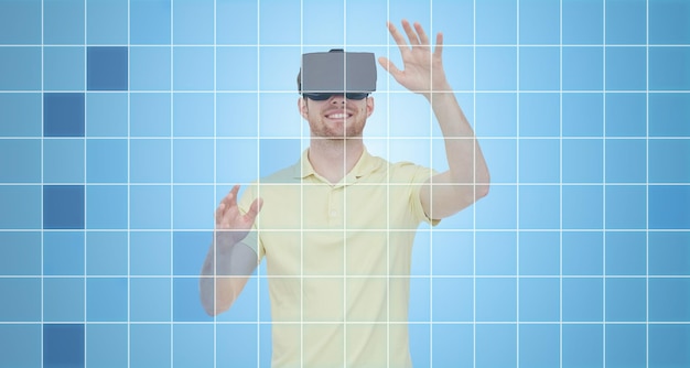 Photo 3d technology, virtual reality, entertainment and people concept - happy young man with virtual reality headset or 3d glasses playing game over blue grid background