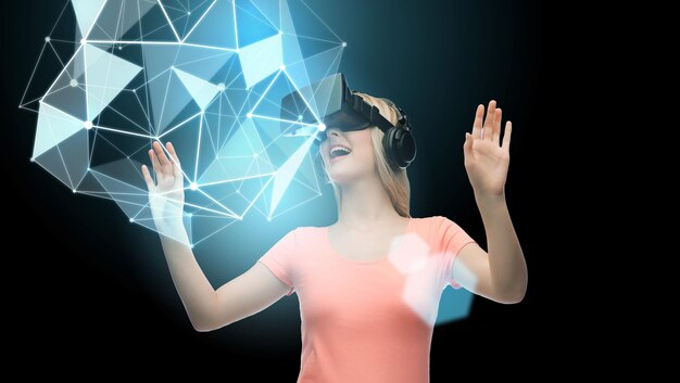 3d technology, virtual reality, entertainment and people concept - happy young woman with virtual reality headset or 3d glasses playing with low poly shape projection over black background