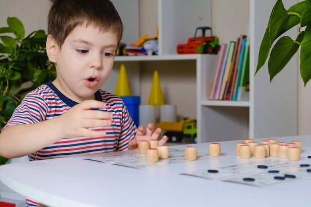 A 4-year-old boy plays loto, studies numbers using a board game.