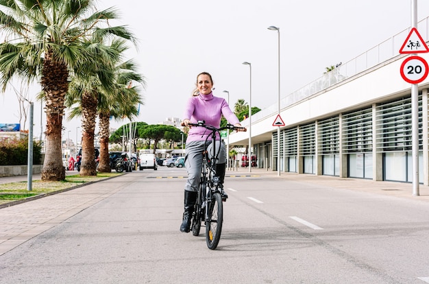 40-year-old woman riding her electric bicycle through the streets of the city (Concept of electric mobility)