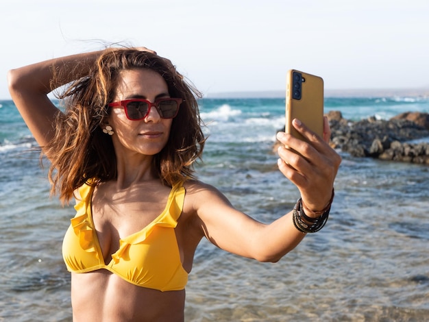 40s Hispanic woman taking self portrait on the beach