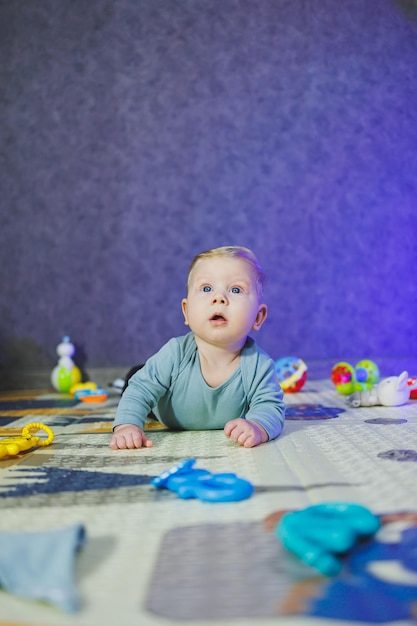 A 4monthold boy lies on a mat and crawls The baby lies on a thermal mat and plays Selfdevelopment of a newborn child Toys for child development